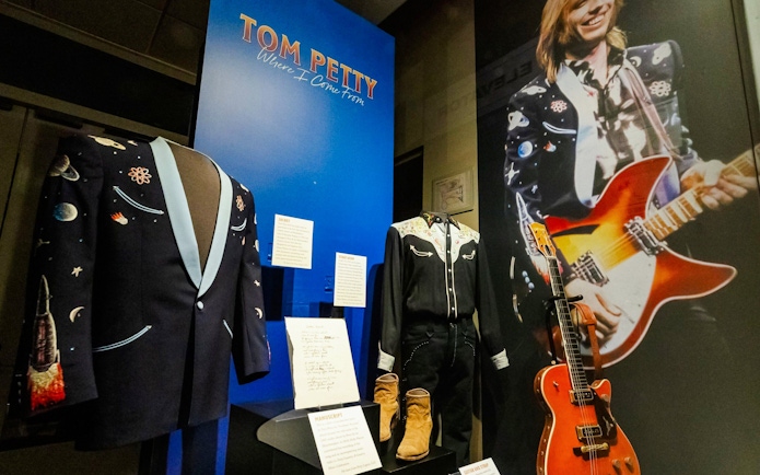 Tom Petty exhibit with stage outfits and guitar at Country Music Hall of Fame.