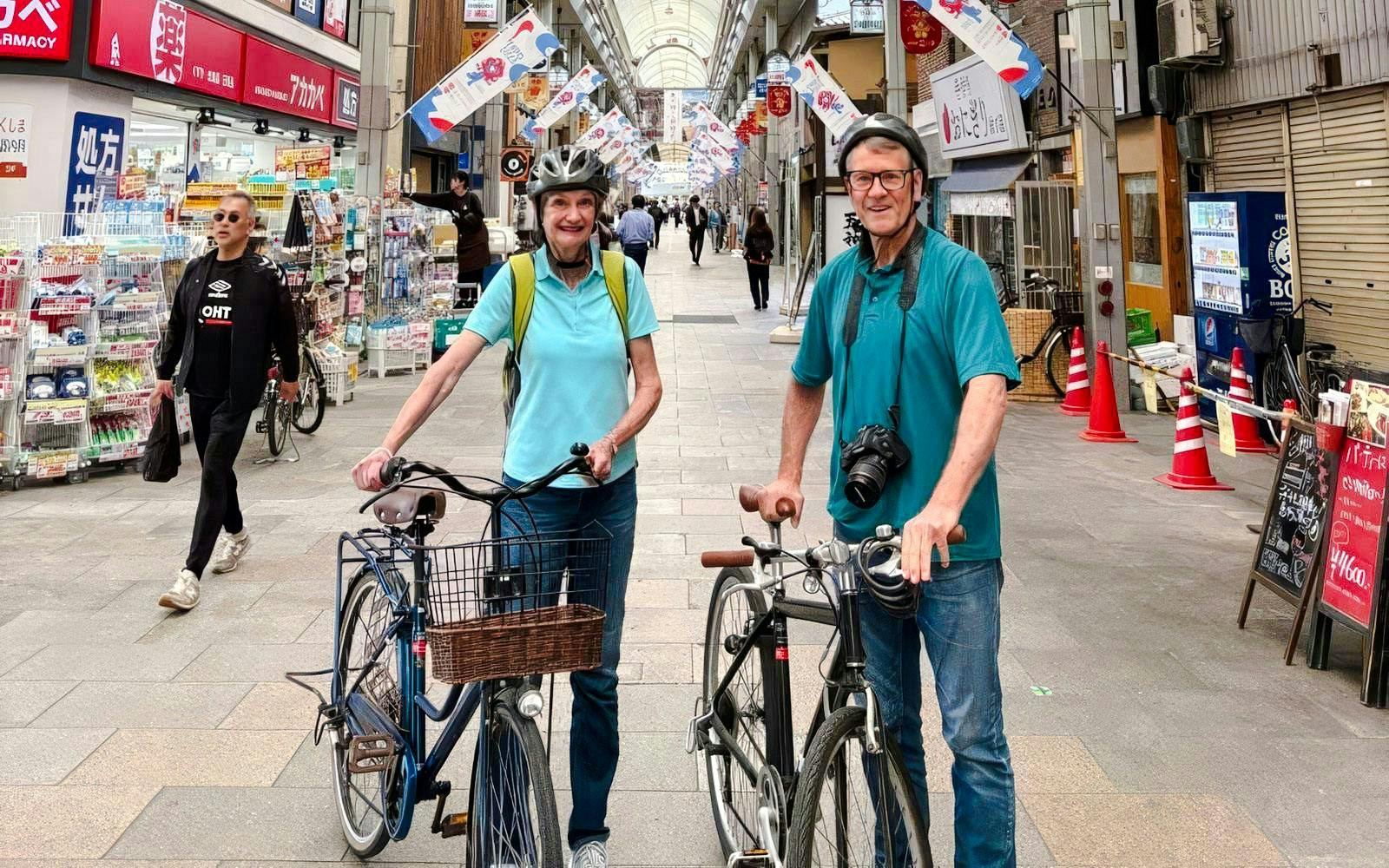 Old couple with bikes in Osaka shopping street during castle tour.