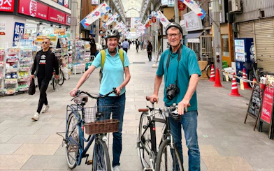 Old couple with bikes in Osaka shopping street during castle tour.