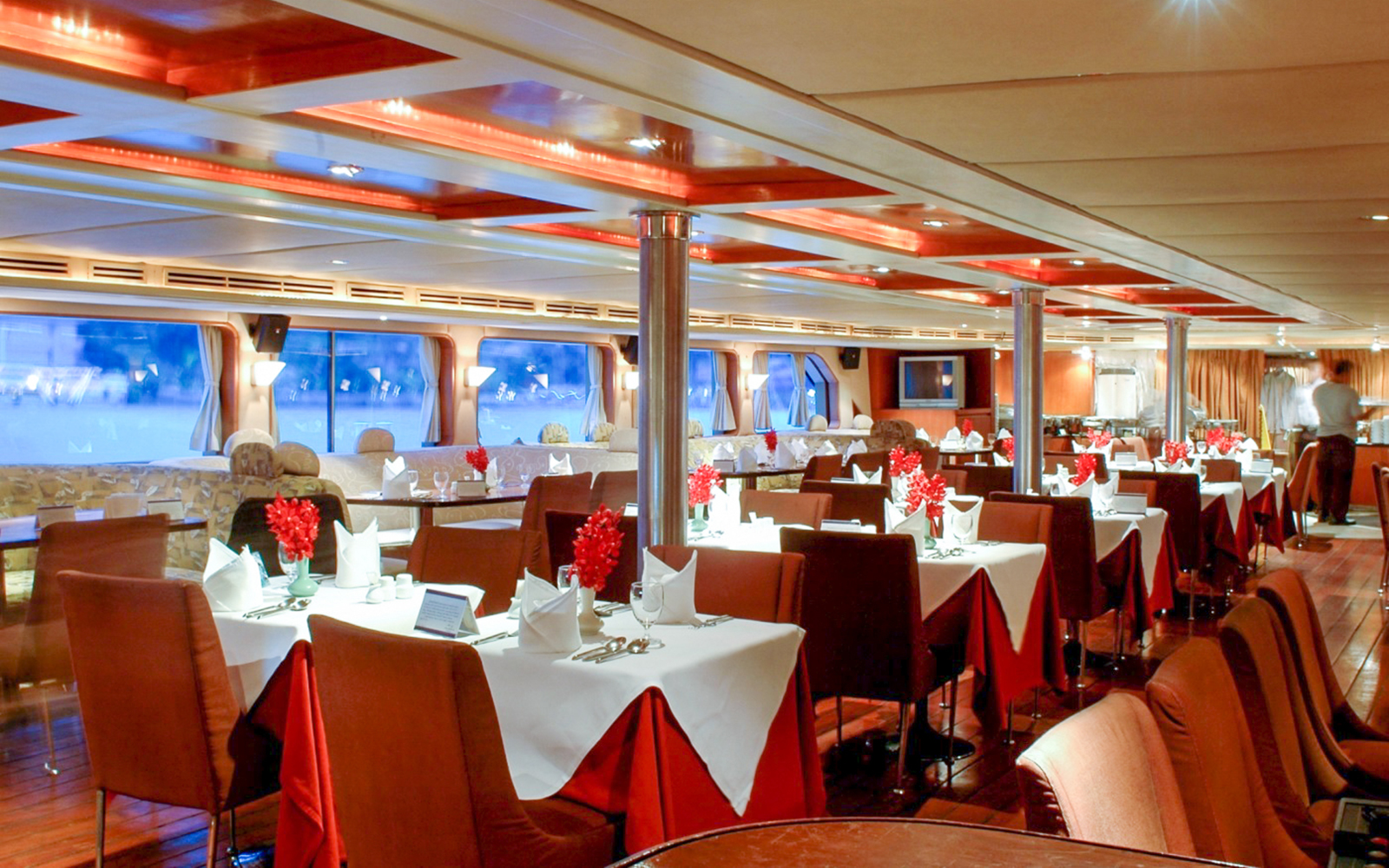 Elegant dining setup on the Grand Pearl Dinner Cruise with tables and red accents.