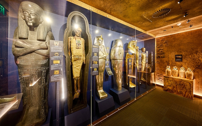 Ancient Egyptian sarcophagi and mummy cases in the Tomb of the Pharaoh exhibit.