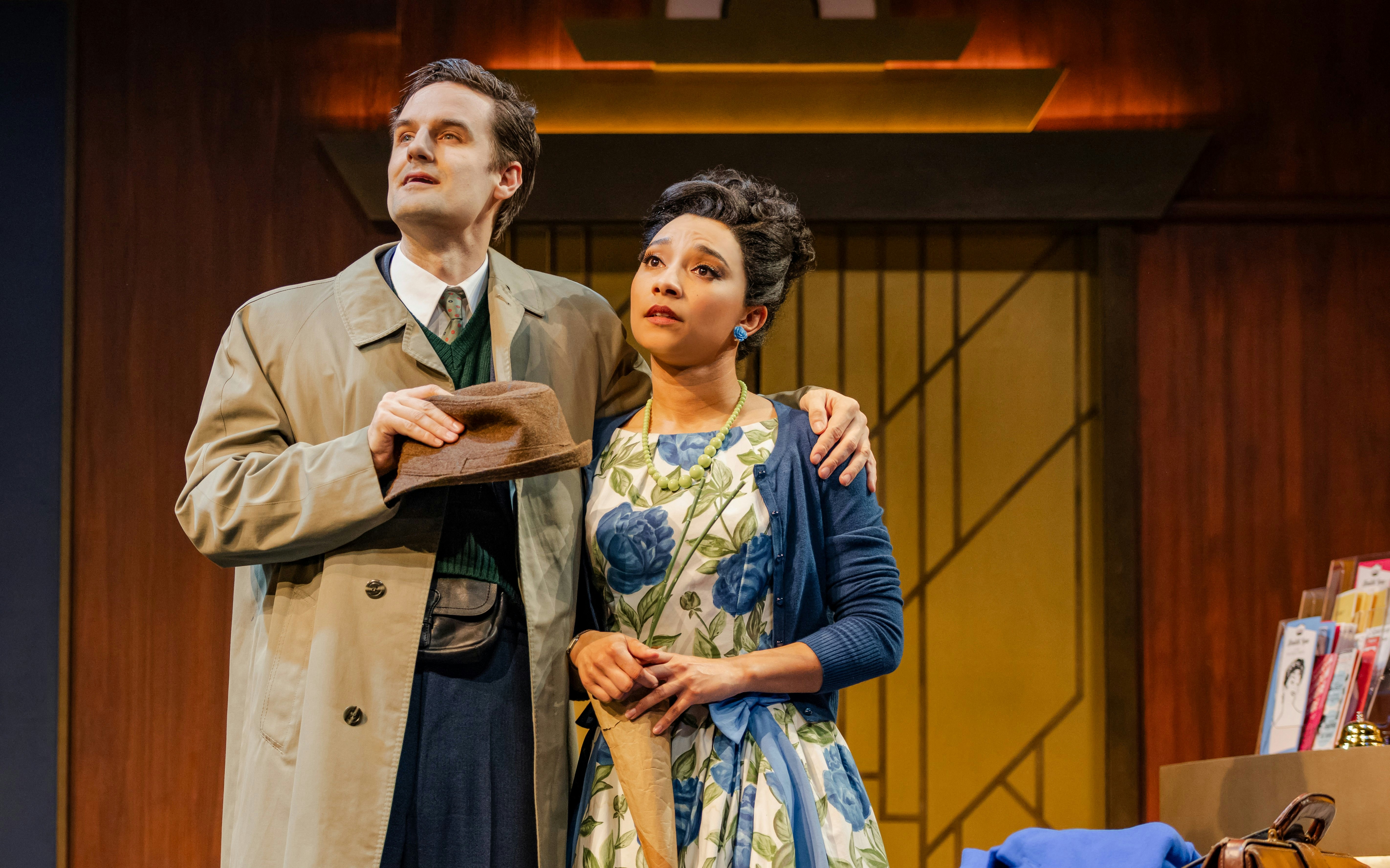 Actors in a scene from "The Comedy About Spies" on stage, with vintage attire and props.