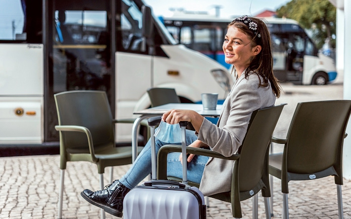 Traveler waiting with luggage for Vesuvius and Herculaneum tour bus in Naples.