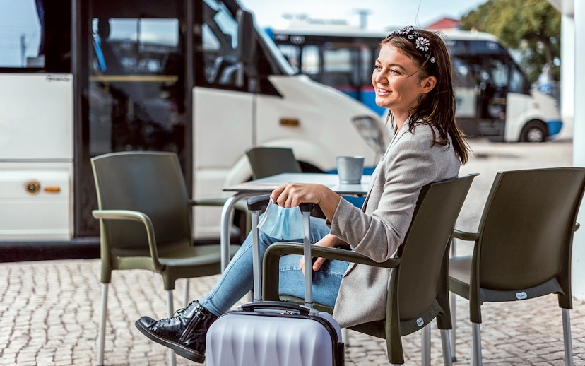 Traveler waiting with luggage for Vesuvius and Herculaneum tour bus in Naples.