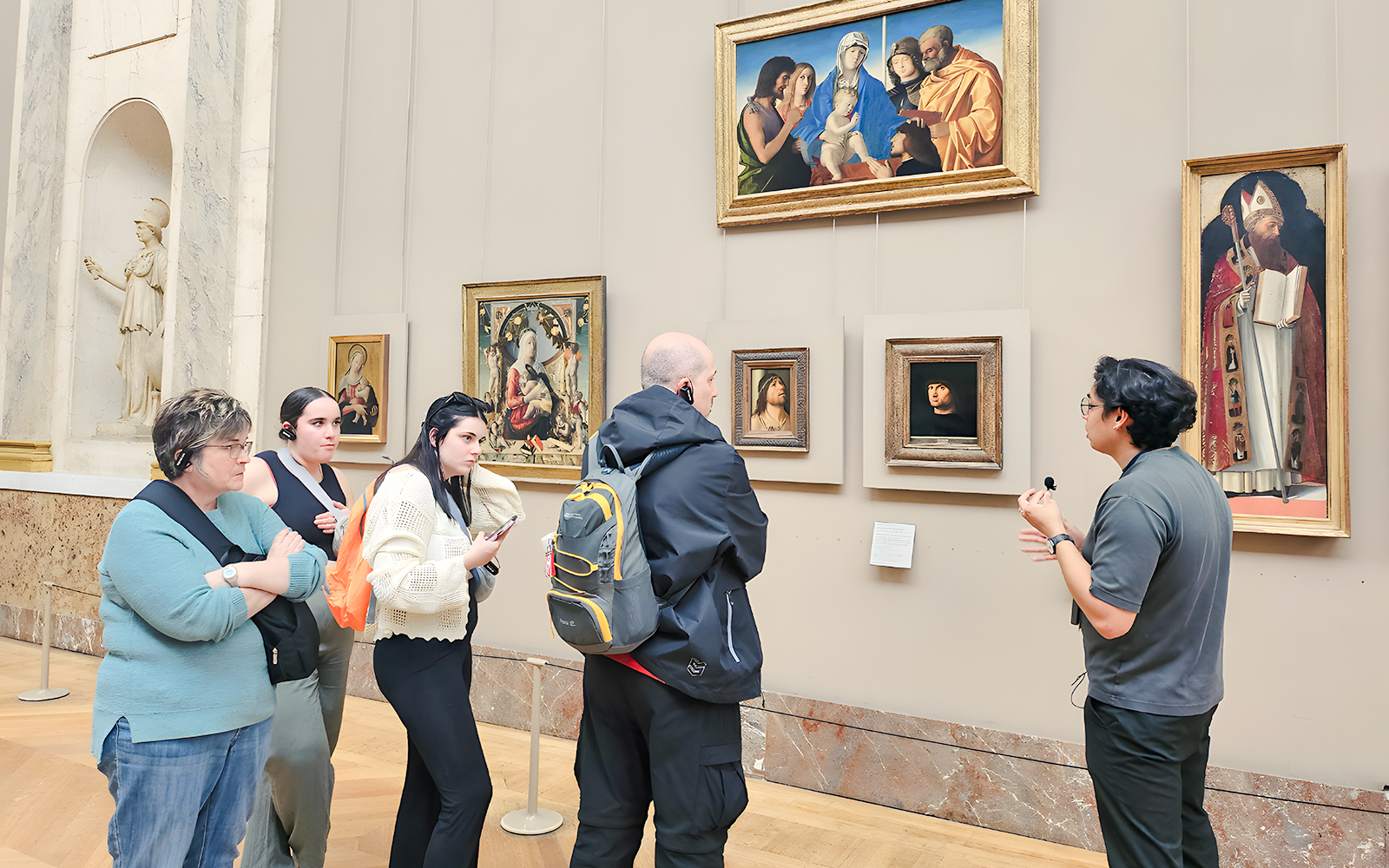 Visitors viewing paintings during a guided tour inside the Louvre Museum, Paris, France.