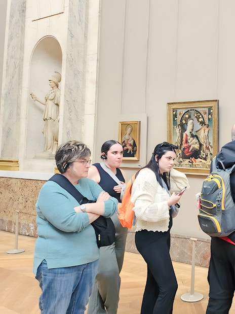 Visitors viewing paintings during a guided tour inside the Louvre Museum, Paris, France.