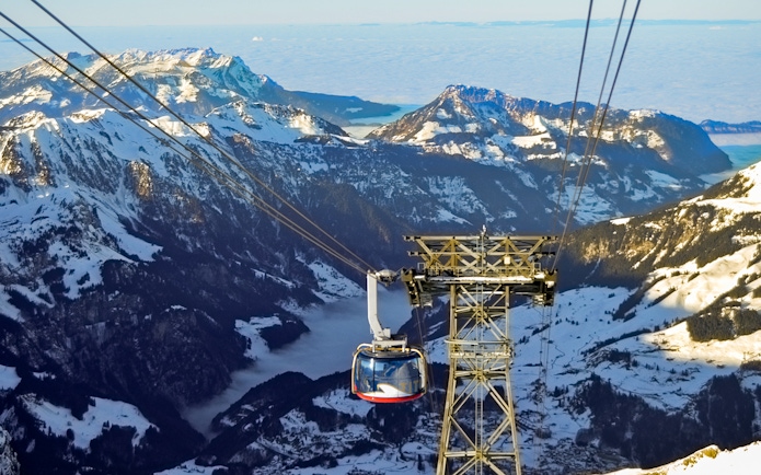 Mount Titlis Rotair cable car ascending snowy Swiss Alps.