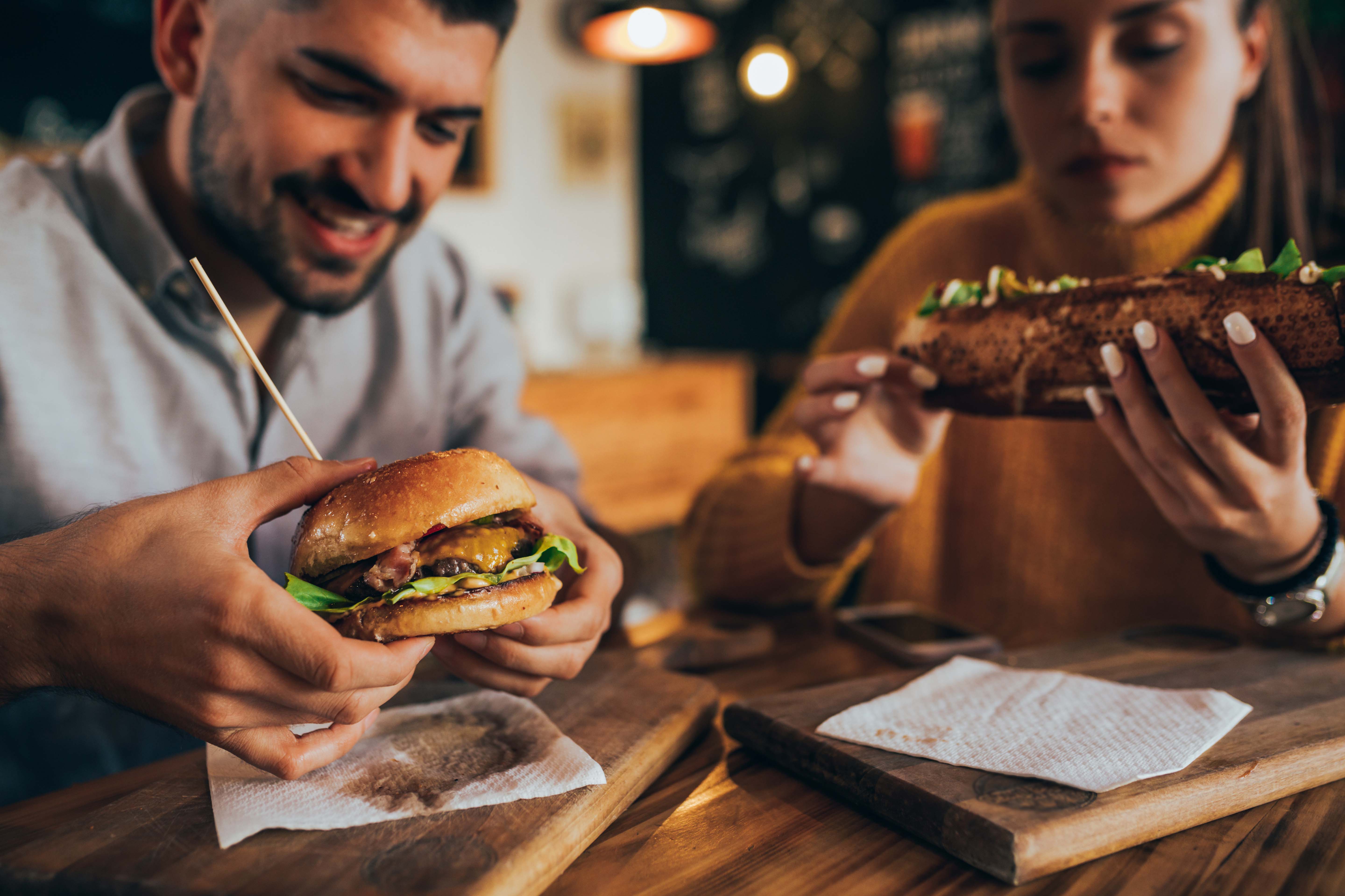 People enjoying burgers and sandwiches at a grill and bar.