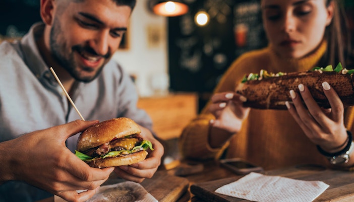 People enjoying burgers and sandwiches at a grill and bar.