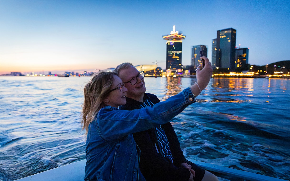 Couple taking a selfie on the Happy Valentine Evening Cruise with city skyline in the background.