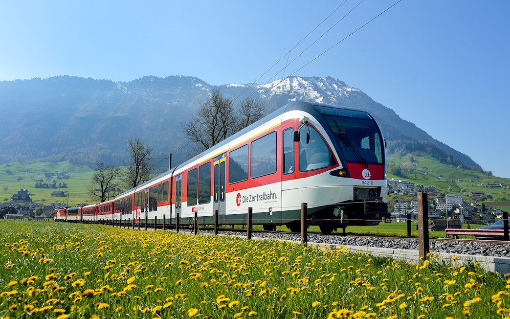 Train traveling through scenic landscapes near Lucerne, Switzerland with mountains in the background.
