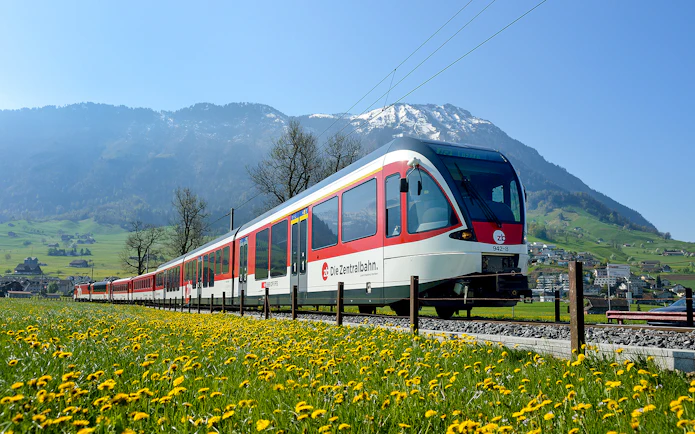 Train traveling through scenic landscapes near Lucerne, Switzerland with mountains in the background.