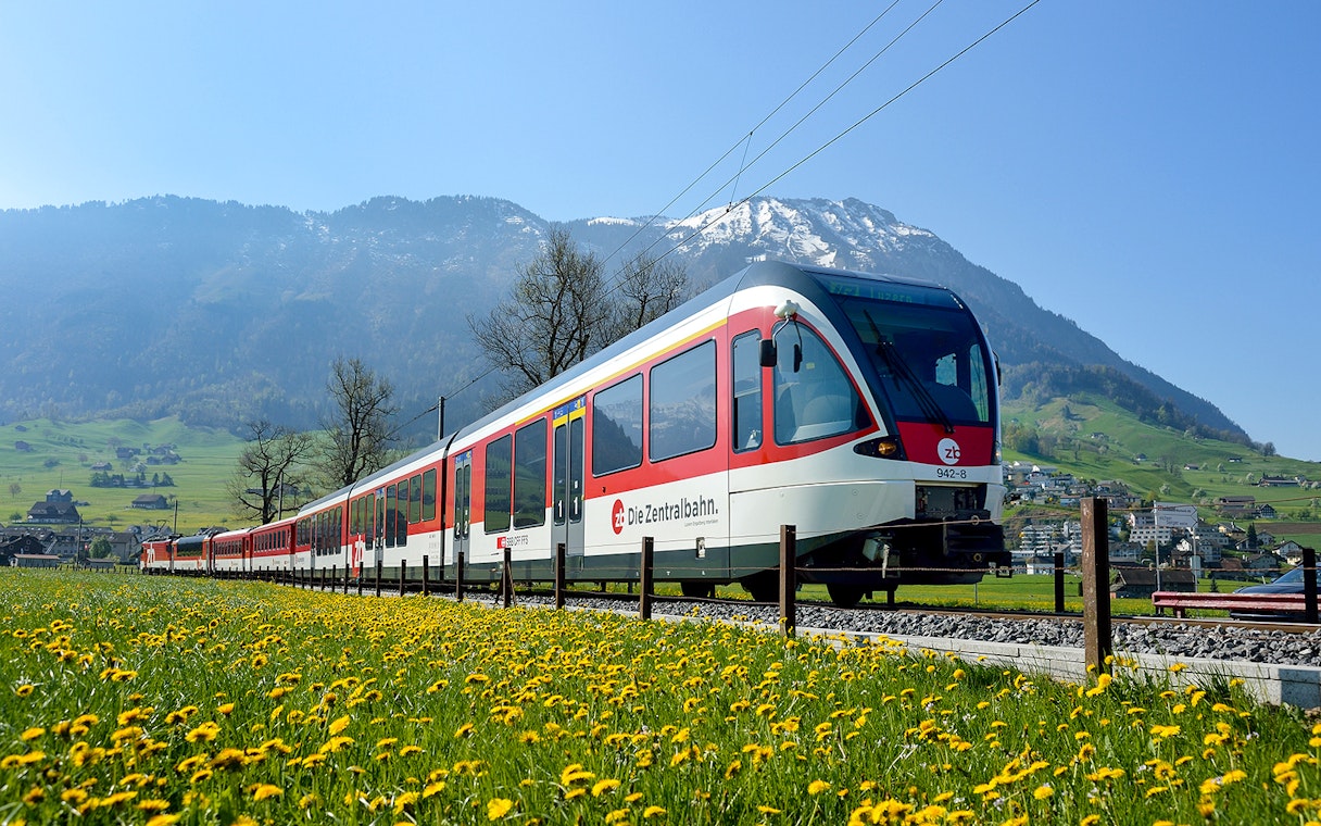 Train traveling through scenic landscapes near Lucerne, Switzerland with mountains in the background.
