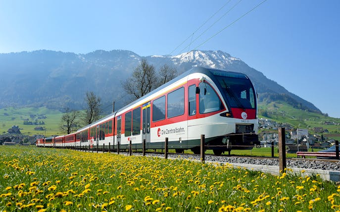 Train traveling through scenic landscapes near Lucerne, Switzerland with mountains in the background.