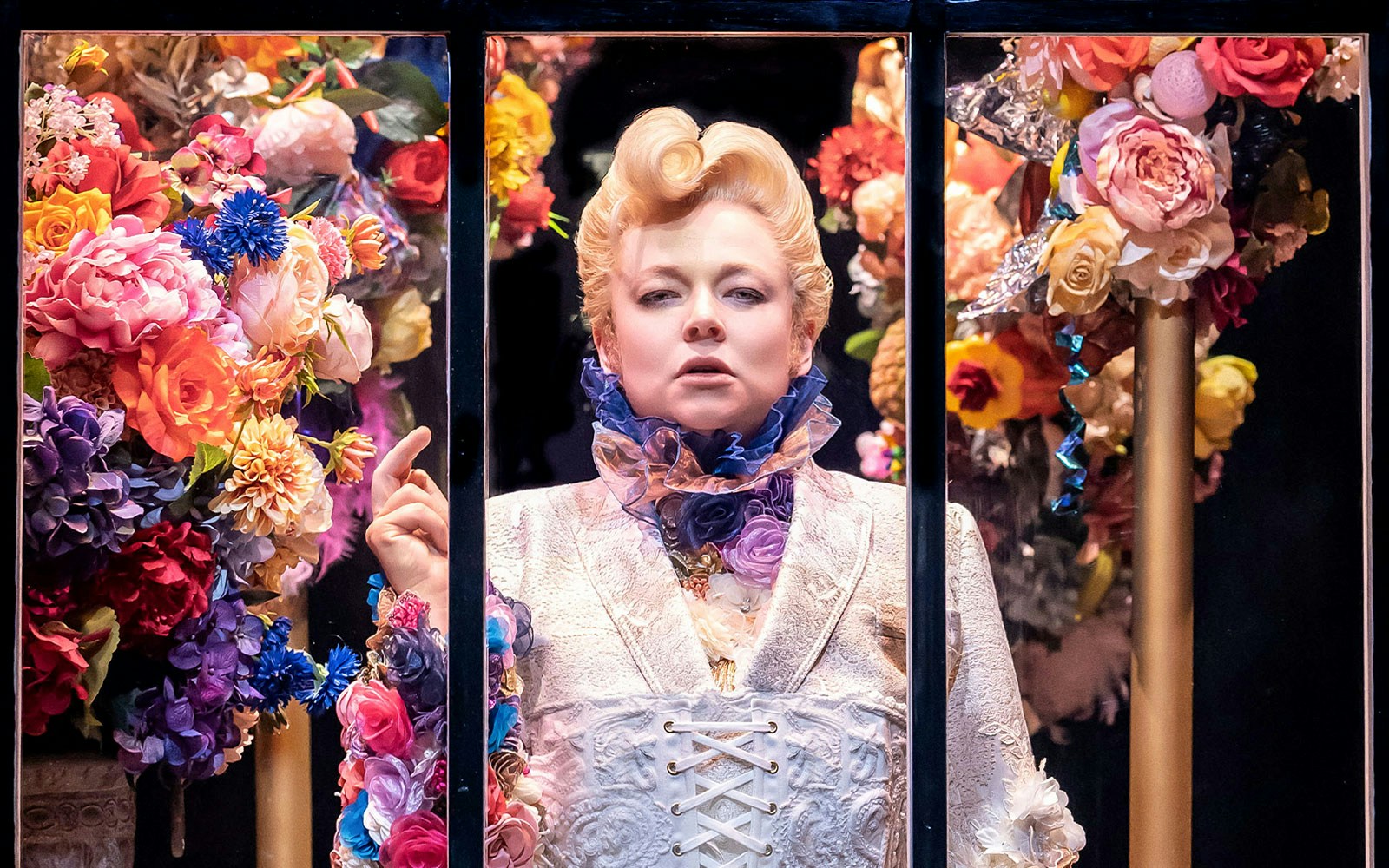 Person in ornate costume surrounded by colorful flowers, related to "The Picture of Dorian Gray.