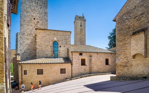 San Gimignano stone towers and historic buildings under a clear blue sky.