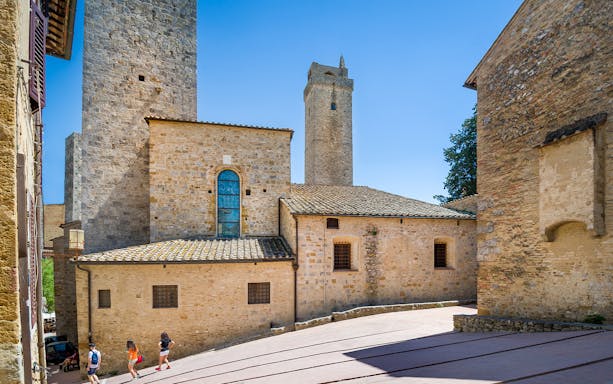 San Gimignano stone towers and historic buildings under a clear blue sky.