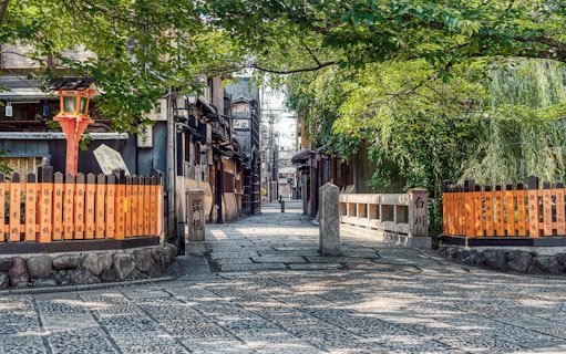 Kyoto traditional street with wooden buildings and orange lanterns, part of Keihan sightseeing tour.