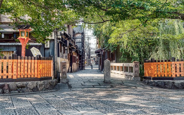 Kyoto traditional street with wooden buildings and orange lanterns, part of Keihan sightseeing tour.