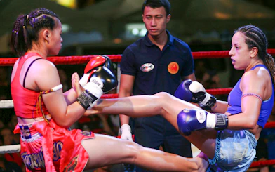 Two fighters in a Muay Thai match at Bangla Boxing Stadium, referee observing.