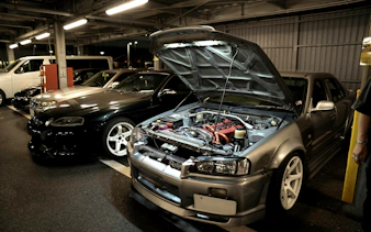 Tokyo car meetup featuring modified JDM vehicles in a parking garage at night.