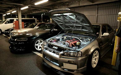 Tokyo car meetup featuring modified JDM vehicles in a parking garage at night.