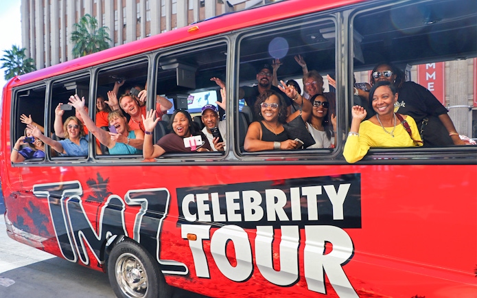 Tourists waving from TMZ Celebrity Tour bus in Hollywood.