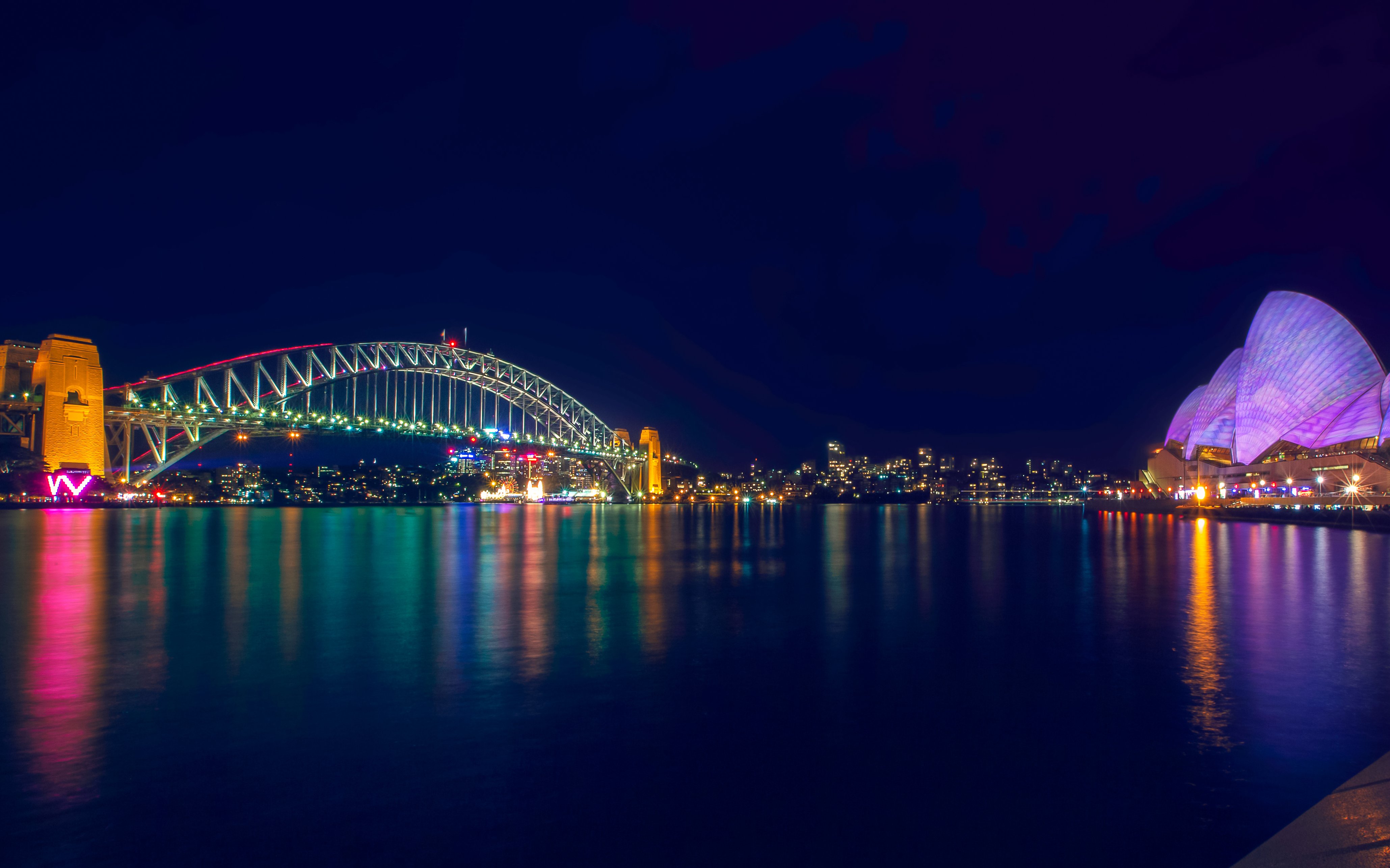 Sydney Harbour Bridge and Opera House illuminated during light show.