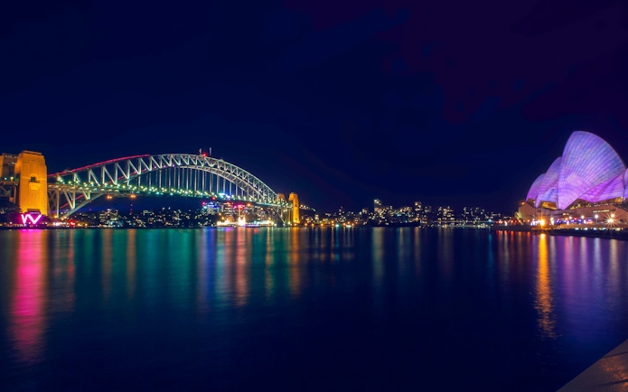 Sydney Harbour Bridge and Opera House illuminated during light show.