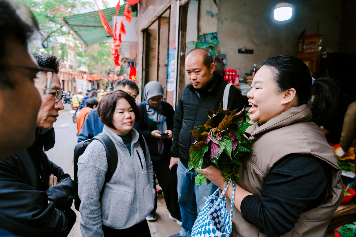 Local host in Hanoi discussing herbs with a group during a Vietnamese family meal tour.