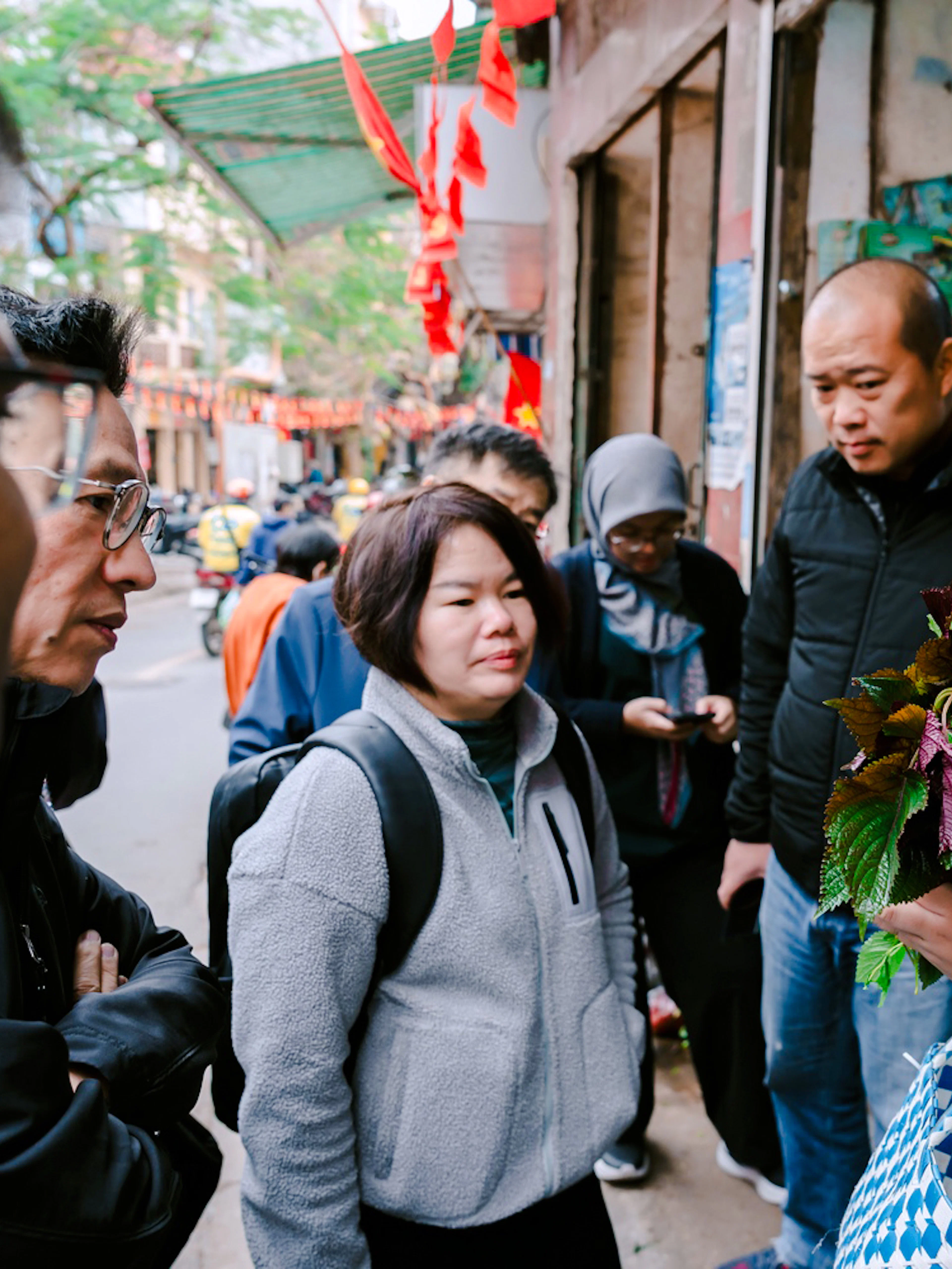 Local host in Hanoi discussing herbs with a group during a Vietnamese family meal tour.