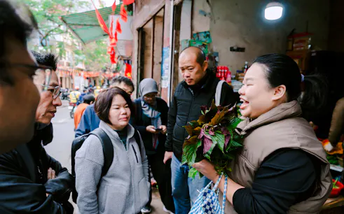 Local host in Hanoi discussing herbs with a group during a Vietnamese family meal tour.