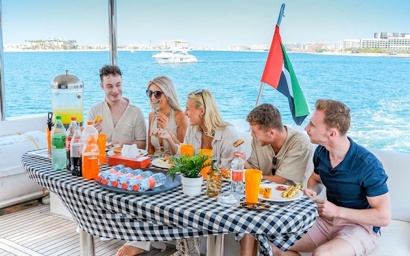 Guests enjoying breakfast on a luxury yacht cruise with ocean view.