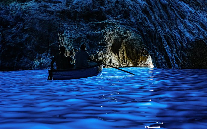 Boat entering the illuminated Blue Grotto cave in Capri, Italy.