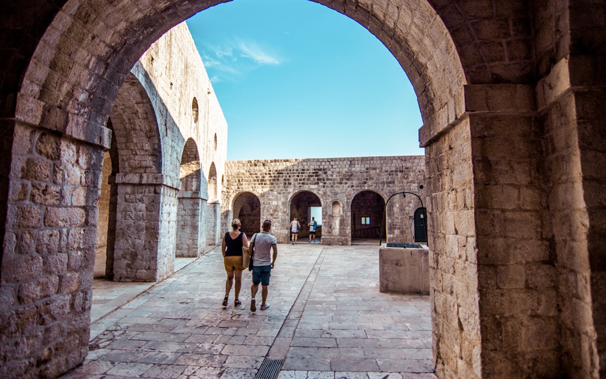 Guests walking through stone arches at Lovrijenac Fort, Dubrovnik.