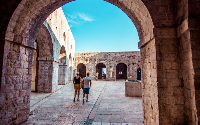 Guests walking through stone arches at Lovrijenac Fort, Dubrovnik.