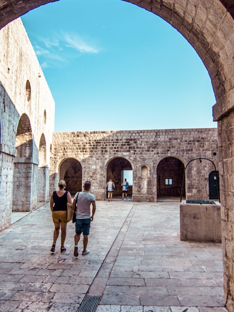Guests walking through stone arches at Lovrijenac Fort, Dubrovnik.