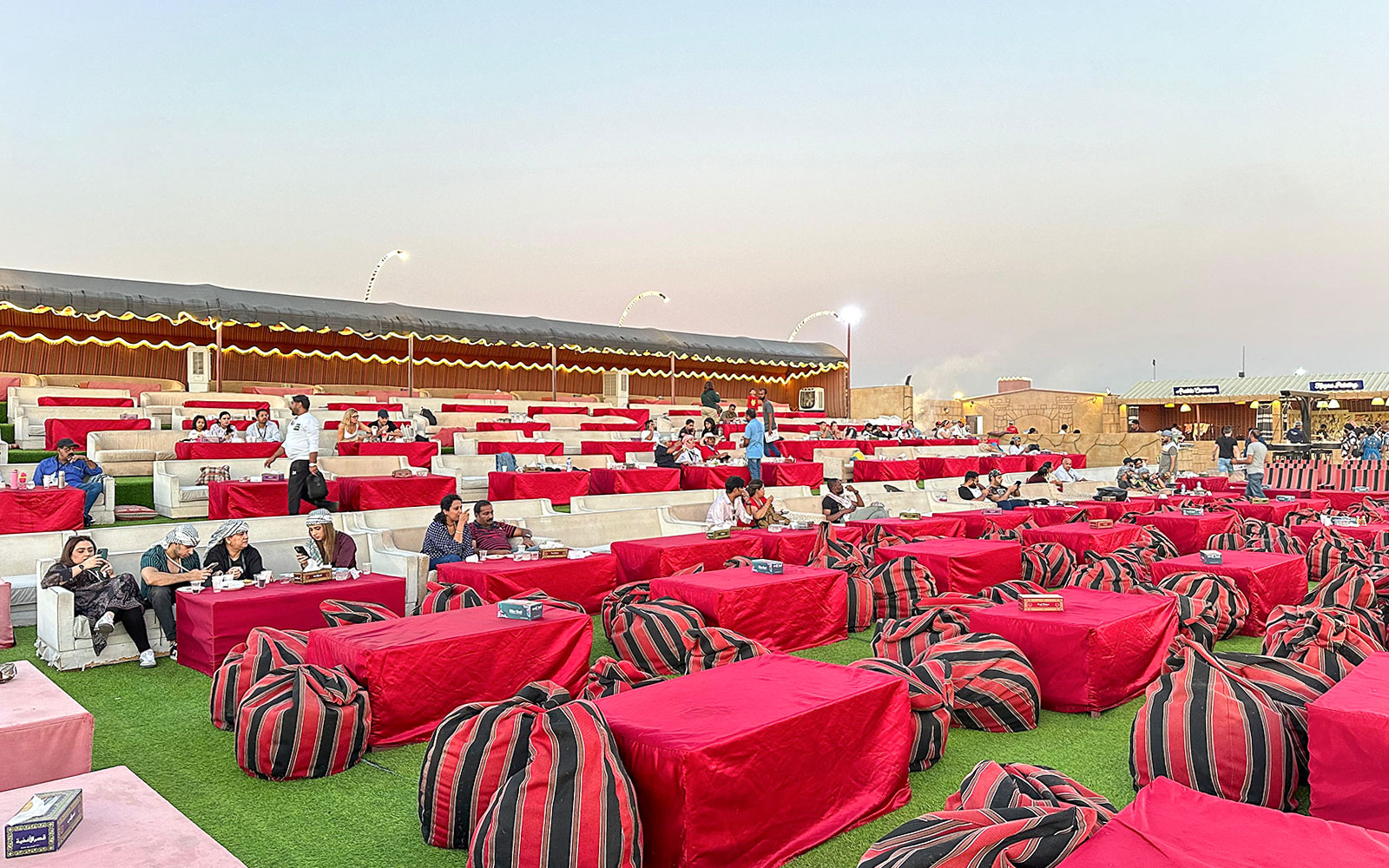 Desert camp seating area for evening safari with guests dining, Dubai.