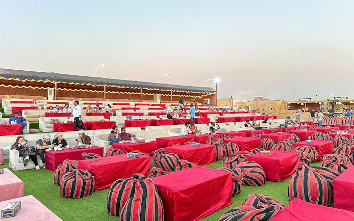 Desert camp seating area for evening safari with guests dining, Dubai.