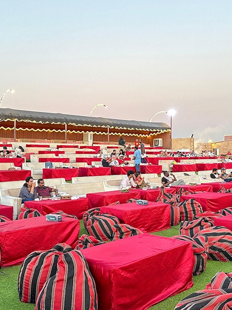 Desert camp seating area for evening safari with guests dining, Dubai.