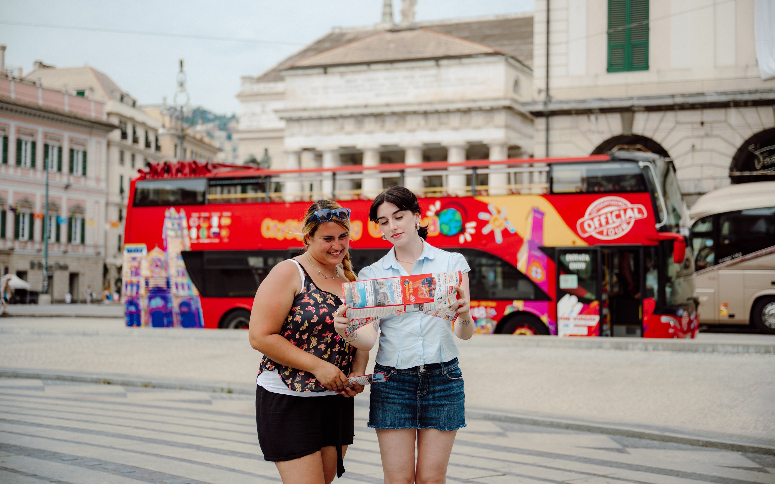 People reading a map in front of a City Sightseeing bus in Genoa, Italy.