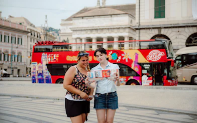 People reading a map in front of a City Sightseeing bus in Genoa, Italy.