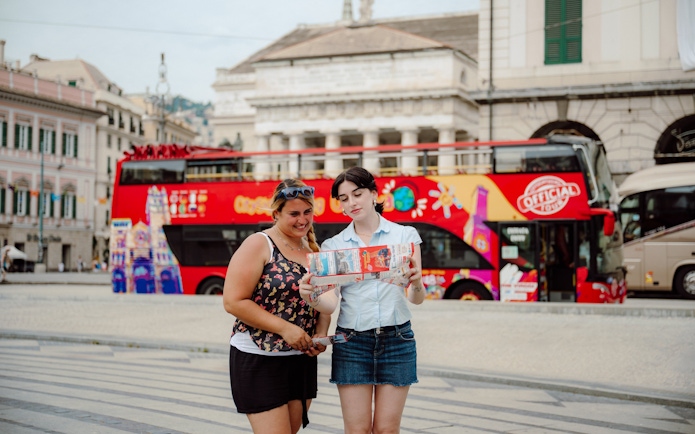 People reading a map in front of a City Sightseeing bus in Genoa, Italy.