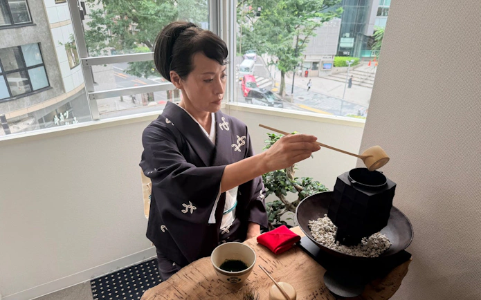 Person in traditional attire preparing matcha during a Kintsugi workshop in Shibuya.