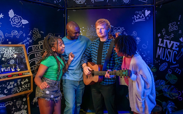 Visitors interacting with Ed Sheeran wax figure at Madame Tussauds London.