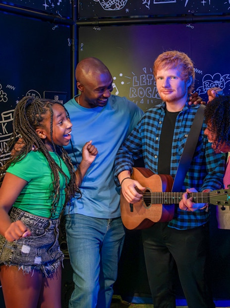 Visitors interacting with Ed Sheeran wax figure at Madame Tussauds London.