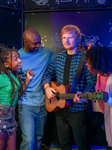 Visitors interacting with Ed Sheeran wax figure at Madame Tussauds London.