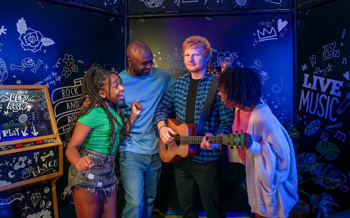 Visitors interacting with Ed Sheeran wax figure at Madame Tussauds London.