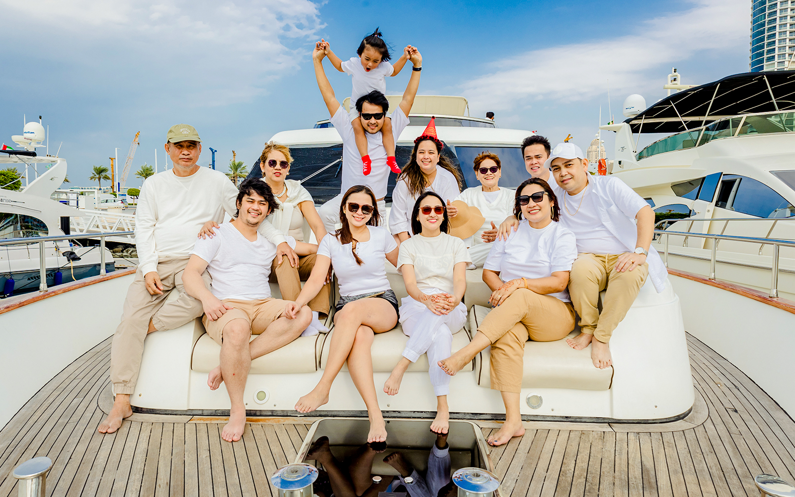 Tourists enjoying a Dubai sunset yacht tour, seated on the deck with cityscape in the background.
