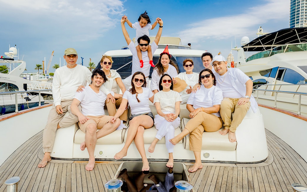 Tourists enjoying a Dubai sunset yacht tour, seated on the deck with cityscape in the background.